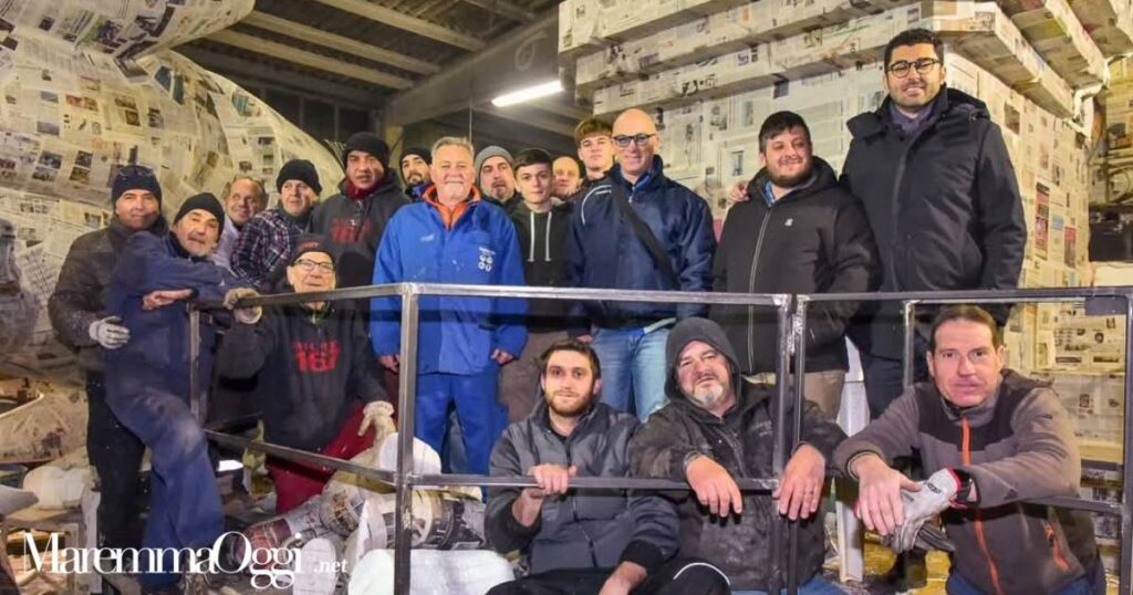 Foto di gruppo dei volontari ripresi a lavoro nel capannone durante la visita del sindaco Buoncristiani